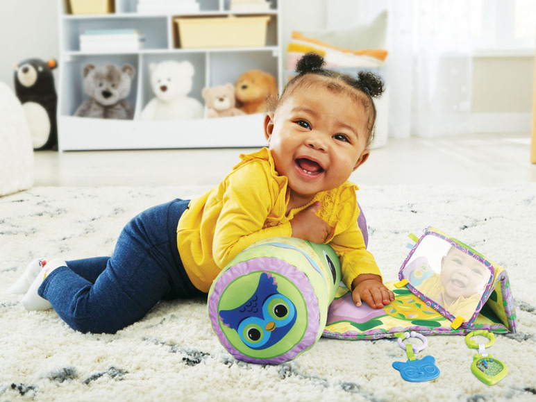 Ein Baby liegt auf einer Spielmatte mit einem Eulenkissen und einem Spiegel.