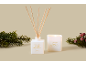 Weihnachtskerze und Diffusor mit Vanille-Schneeflocken-Duft, mit Tannenzweigen.