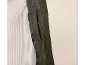 Grüne Jacke mit Tasche über einem grauen Waffelstrickpullover.