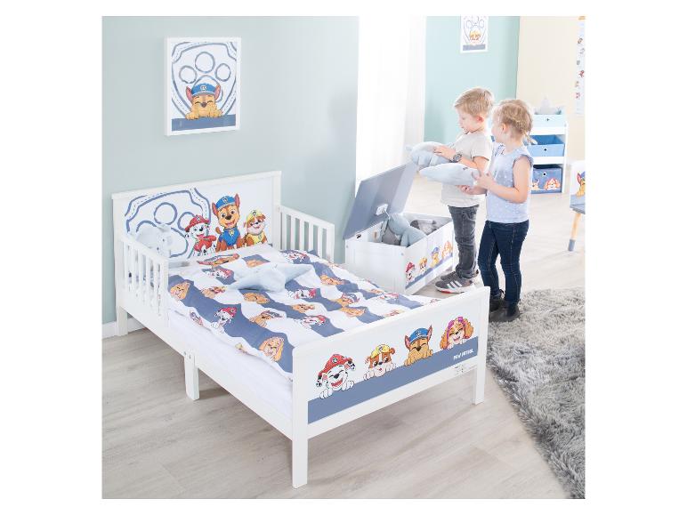 Weißes Kinderbett mit Welpenmotiv und zwei spielenden Kindern im Kinderzimmer.