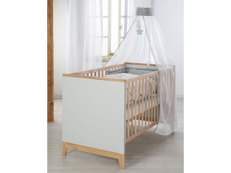 Ein Babybett mit einem weißen Moskitonetz und einem grauen Muster.