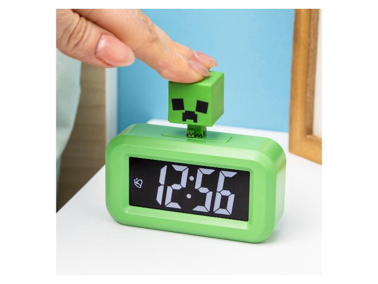 Grüner Minecraft Creeper Wecker, bei dem eine Hand die Oberseite drückt