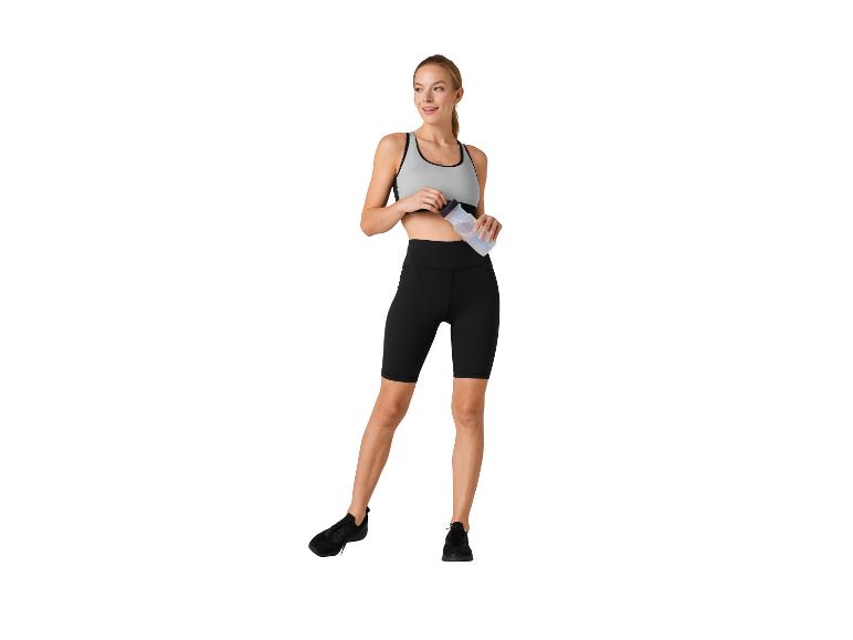 Frau in Sportkleidung: Top, Radlerhose und Wasserflasche.