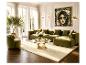 Elegantes Wohnzimmer mit olivgrünem Sofa, Sessel, Glas-Couchtisch und hellem Teppich.