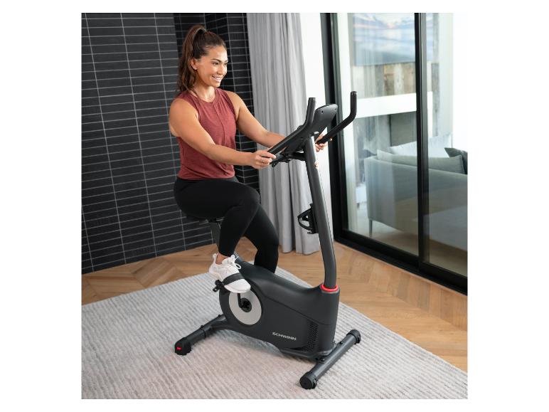 Frau in Sportkleidung fährt auf einem Heimtrainer in einem modernen Raum.