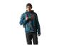 Mann in einer teal- und grauen Outdoorjacke mit orangefarbenen Reißverschlüssen, schwarzer Mütze und Rucksack.
