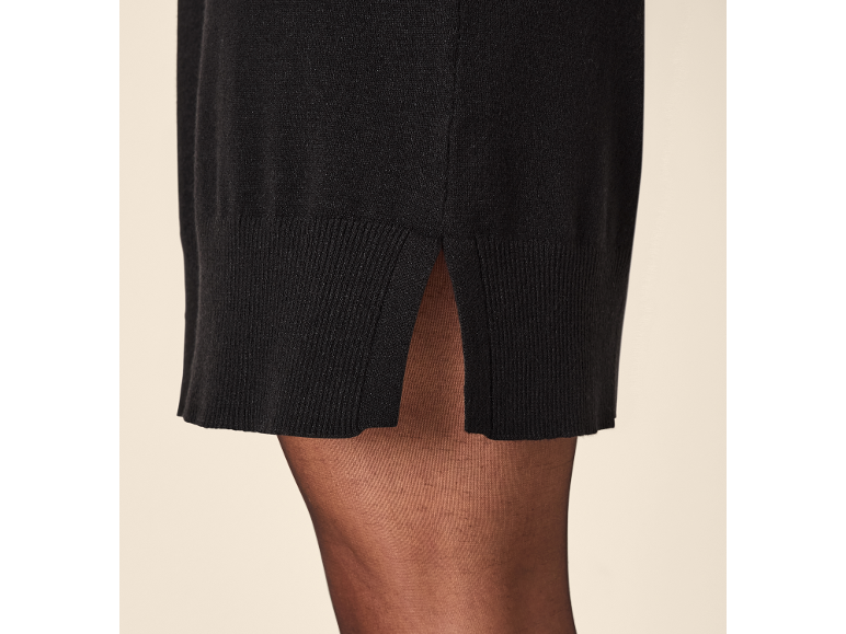 Schwarzes Strickkleid mit Schlitz und schwarze Strumpfhose.