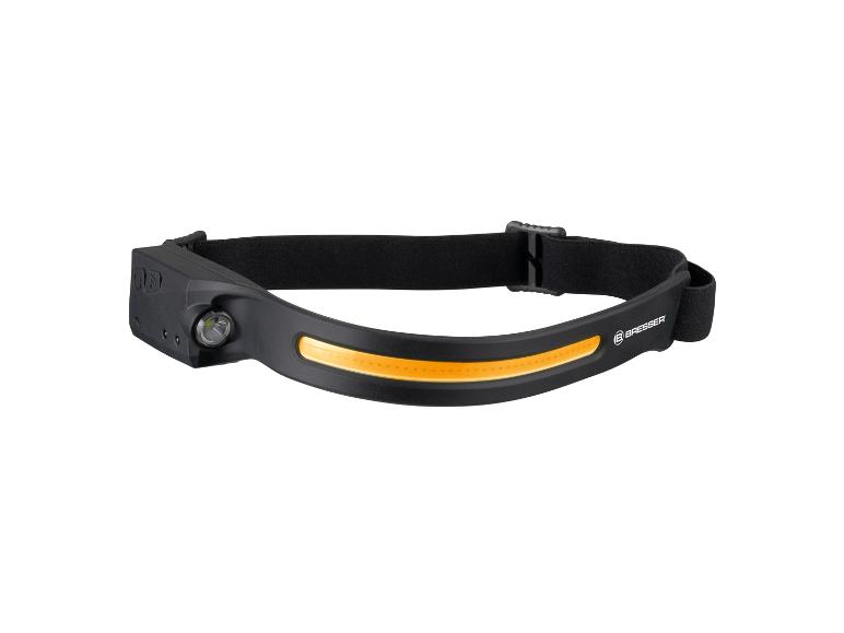 Eine schwarze Bresser Stirnlampe mit einem orangefarbenen Leuchtstreifen.
