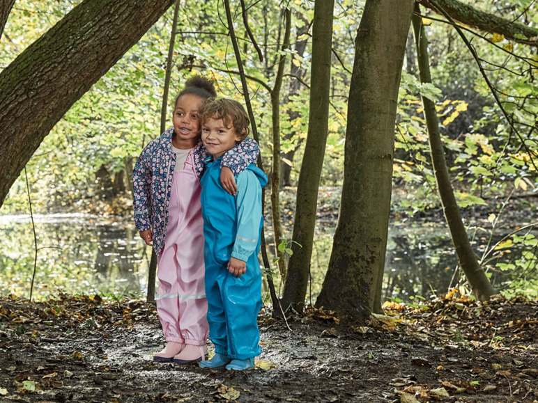 Zwei Kinder in Regenkleidung, mit einem rosa und blauen Regenanzug.