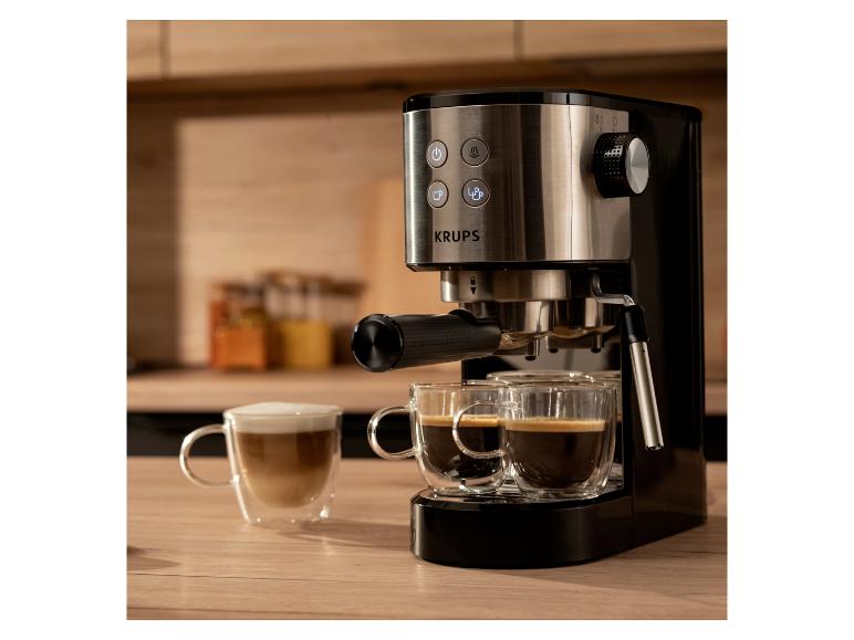 Kaffeemaschine mit zwei Espressotassen und einem Latte auf einer Holzarbeitsplatte.