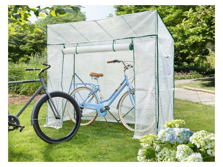 Zwei Fahrräder, ein hellblaues und ein graues, in einem transparenten Fahrradschuppen auf einem Rasen.