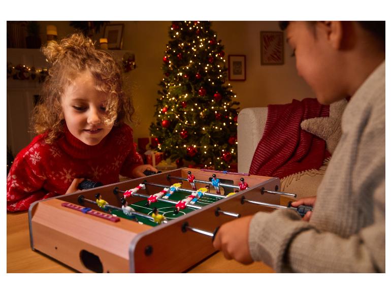 Kinder spielen Tischfußball neben dem Weihnachtsbaum
