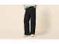 Damen-Hose in Schwarz mit weitem Bein, hellgrünem Pullover und Sneakern.