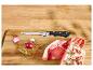 Rohe Lamm- und Schweinekoteletts mit Kräutern, Zwiebel, Knoblauch und einem Küchenmesser auf einem Holzbrett.