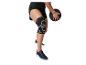 Person in schwarzen Sportshorts, Kniebandage und Turnschuhen, die einen Medizinball hält.