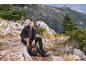 Mann in Fleecejacke und Trekkinghose sitzt auf einem Felsen mit Rucksack und Flasche.