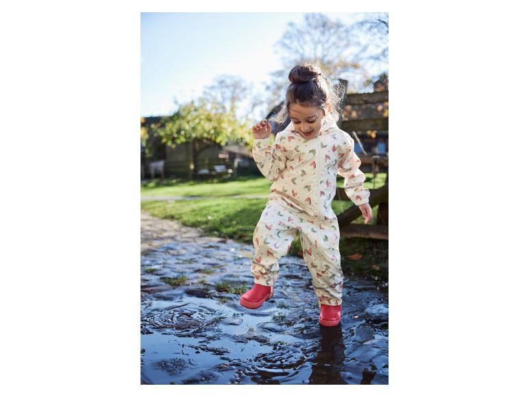 Ein Kind in einem Regenanzug mit Schmetterlingsmuster springt in eine Pfütze.