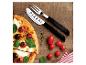 Pizzaset mit Messer und Gabel, neben Pizza mit Tomaten und Oliven auf Holzuntergrund.
