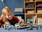 Ein Mädchen spielt mit LEGO® NINJAGO® Sets, darunter ein Boot und ein Roboter.