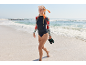 Frau in Langarmshirt, Bikinihose und Schnorchelmaske geht am Strand entlang.