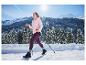 Frau in CRIVIT Thermo-Softshelljacke und lila Leggings wandert in verschneiter Berglandschaft.