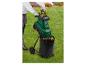 Person im Garten benutzt einen grünen Gartenhäcksler mit schwarzem Auffangsack.