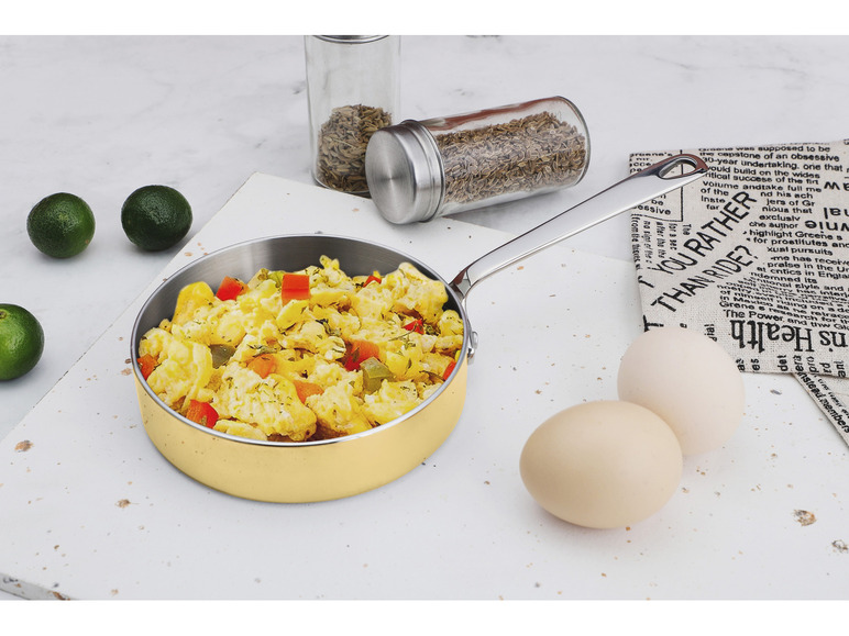 Eine Pfanne mit Rührei, Eiern und Gewürzen auf einem Marmoruntergrund.