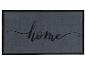 Eine graue Fußmatte mit schwarzem Rand und dem Schriftzug 'home' in Kalligraphie.