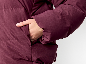 Nahaufnahme einer Frauenhand in der Tasche einer weinroten Daunenjacke.