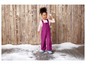 Ein Mädchen in einem lila Overall und blauen Stiefeln spielt mit Schnee.