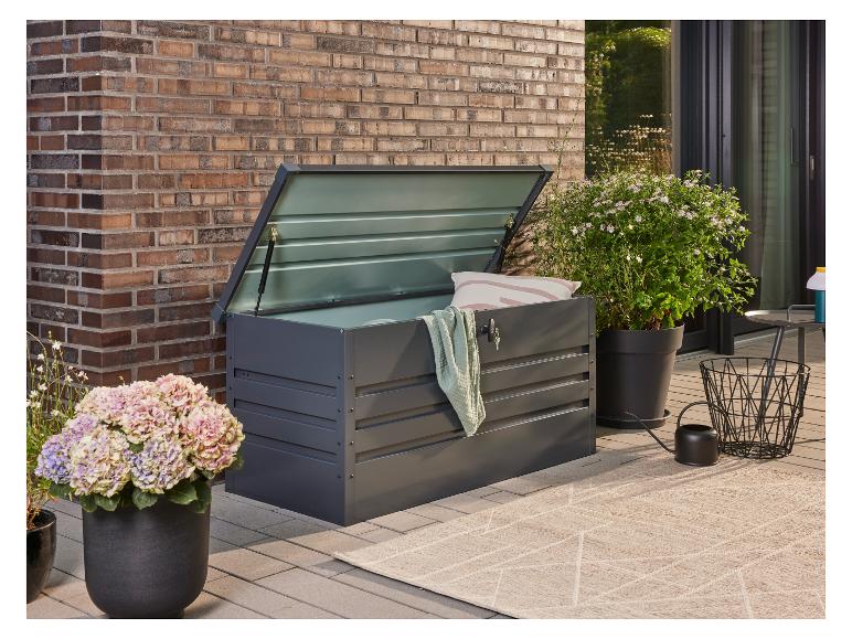 Dunkelgraue Gartenbox mit offenem Deckel, neben Topfpflanzen auf einer Terrasse.