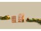 Zwei beleuchtete Keramikhäuser mit Weihnachtsschmuck aus Tannenzweigen und einer goldenen Kugel.