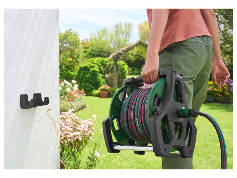 Person hält einen Parkside Gartenschlauch auf einer Halterung im Garten.
