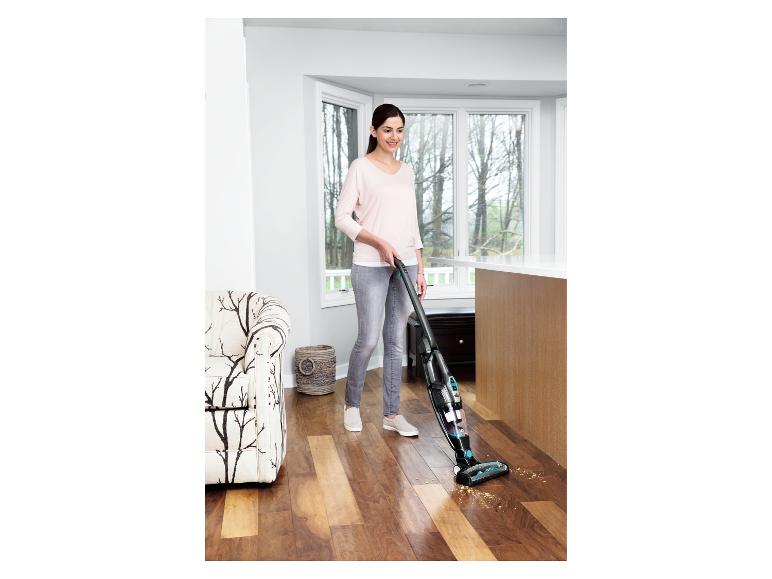 Frau saugt einen Holzboden in einem modernen Wohnbereich.