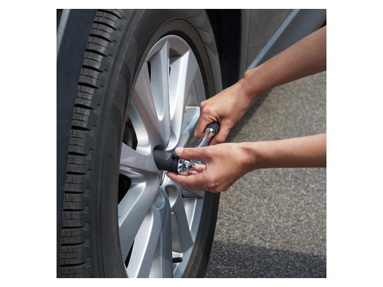 Hände verwenden einen Steckschlüssel, um eine Radmutter am Auto festzuziehen.