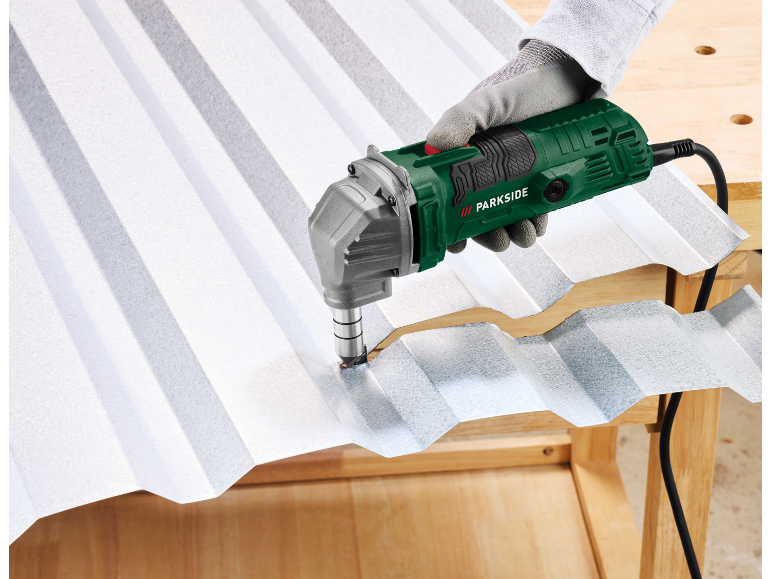 Elektrische Knabber schneidet Wellblech auf einem Holztisch