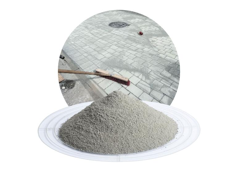 Fugensand für Pflastersteine auf einem Tablett, im Hintergrund eine gepflasterte Fläche.