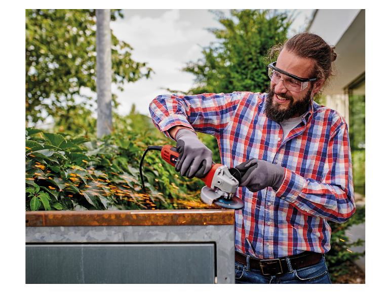 Mann mit Winkelschleifer und Schutzbrille schneidet Metall, Funken fliegen.