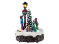 Beleuchtete Weihnachtsdekoration mit Kinderfiguren, Tannenbaum und Straßenlaterne.