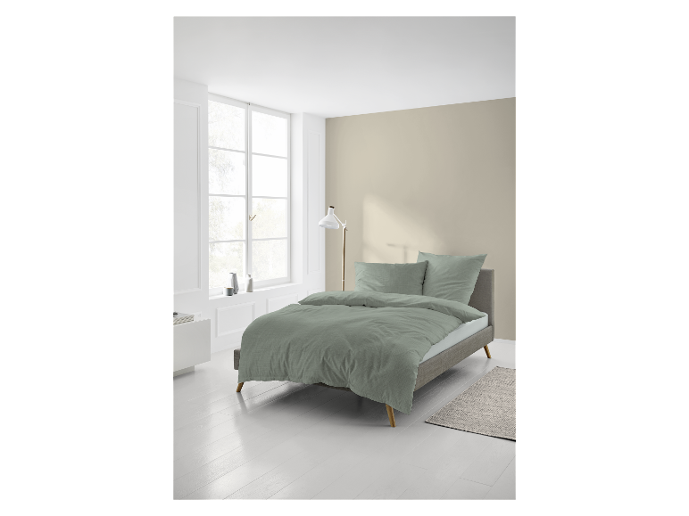 Hellgrünes Bettwäsche-Set und Kissen auf einem modernen Bett.