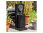 Moderner schwarzer Gartenbrunnen mit Wasser, das in ein geriffeltes Becken fließt, umgeben von Topfpflanzen.