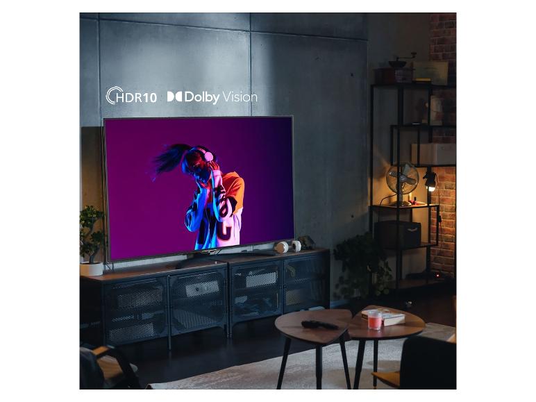 Fernseher mit HDR10 und Dolby Vision zeigt tanzende Frau in modernem Wohnzimmer.