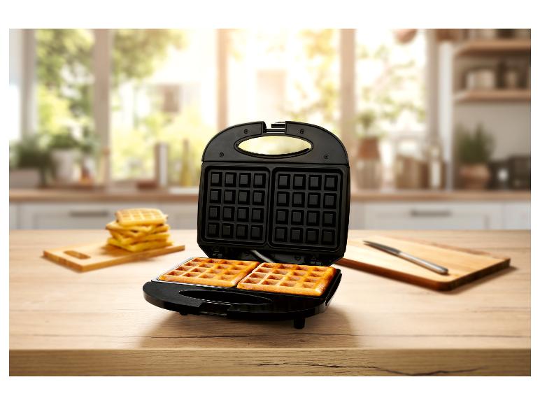 Frische Waffeln und Waffeleisen auf einer Küchentheke.