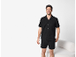Lächelnder Mann in schwarzem Sommerpyjama, Kurzarmhemd und Shorts.