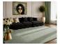 Modernes Wohnzimmer mit schwarzem Sofa, hellgrünem Teppich, goldenem Couchtisch und Wandbild.