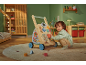 Kleinkind spielt mit einem multifunktionalen Holz-Lauflernwagen in einem grünen Kinderzimmer.