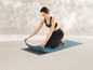 Eine Frau rollt eine blaue Yogamatte aus.