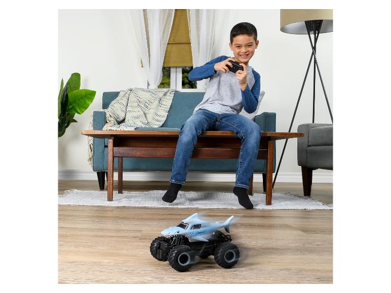 Ein Junge spielt mit einem blauen Monstertruck mit Hai-Motiv.