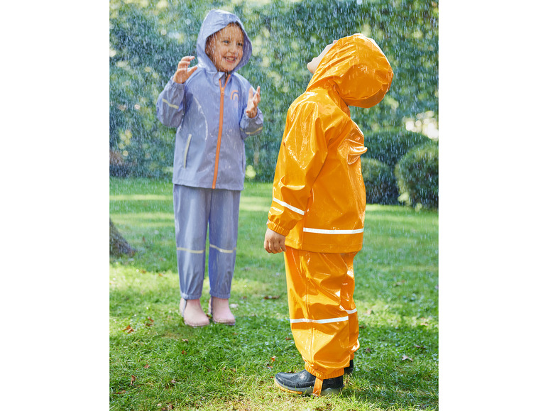 Zwei Kinder spielen im Regen in Regenkleidung.
