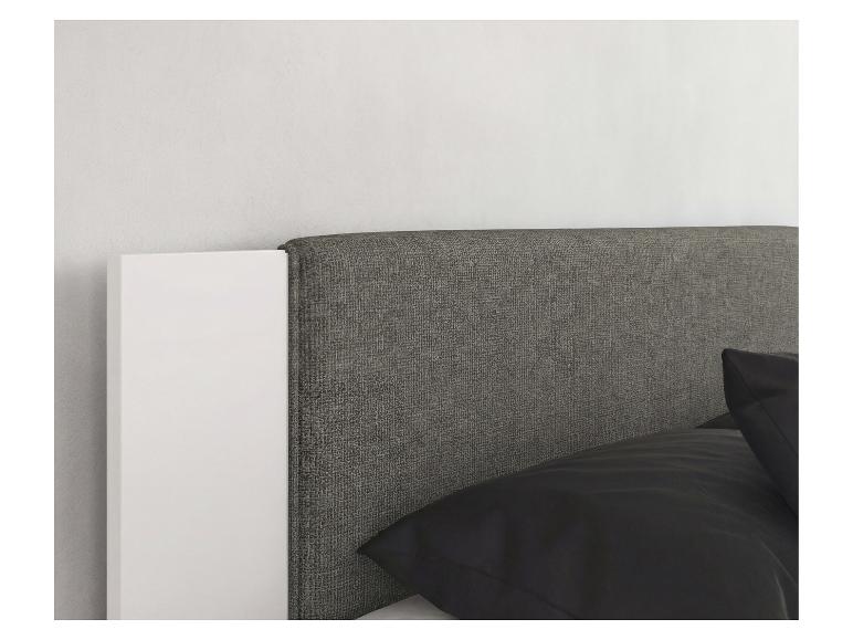 Graues Bettkopfteil mit weißer Seitenblende und schwarzen Kissen.